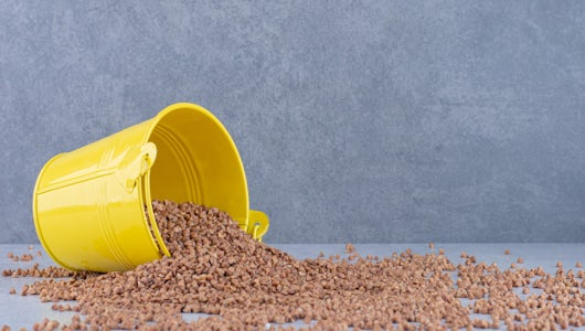 yellow side-lying yellow bucket with grains spilling out on grey surface