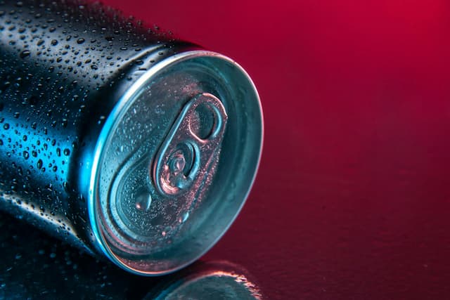 close up of energy drink can on its side against red background