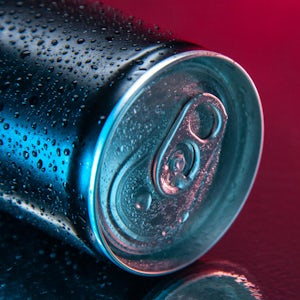 close up of energy drink can on its side against red background