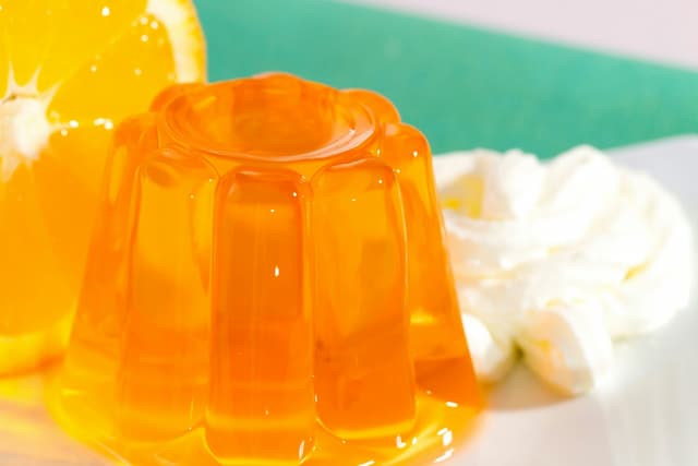 set orange jelly on a plate with whipped cream in the background