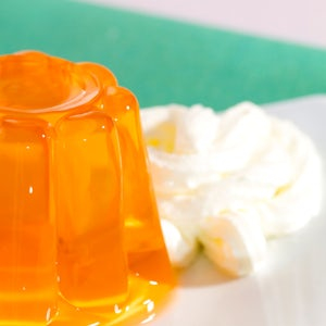 set orange jelly on a plate with whipped cream in the background