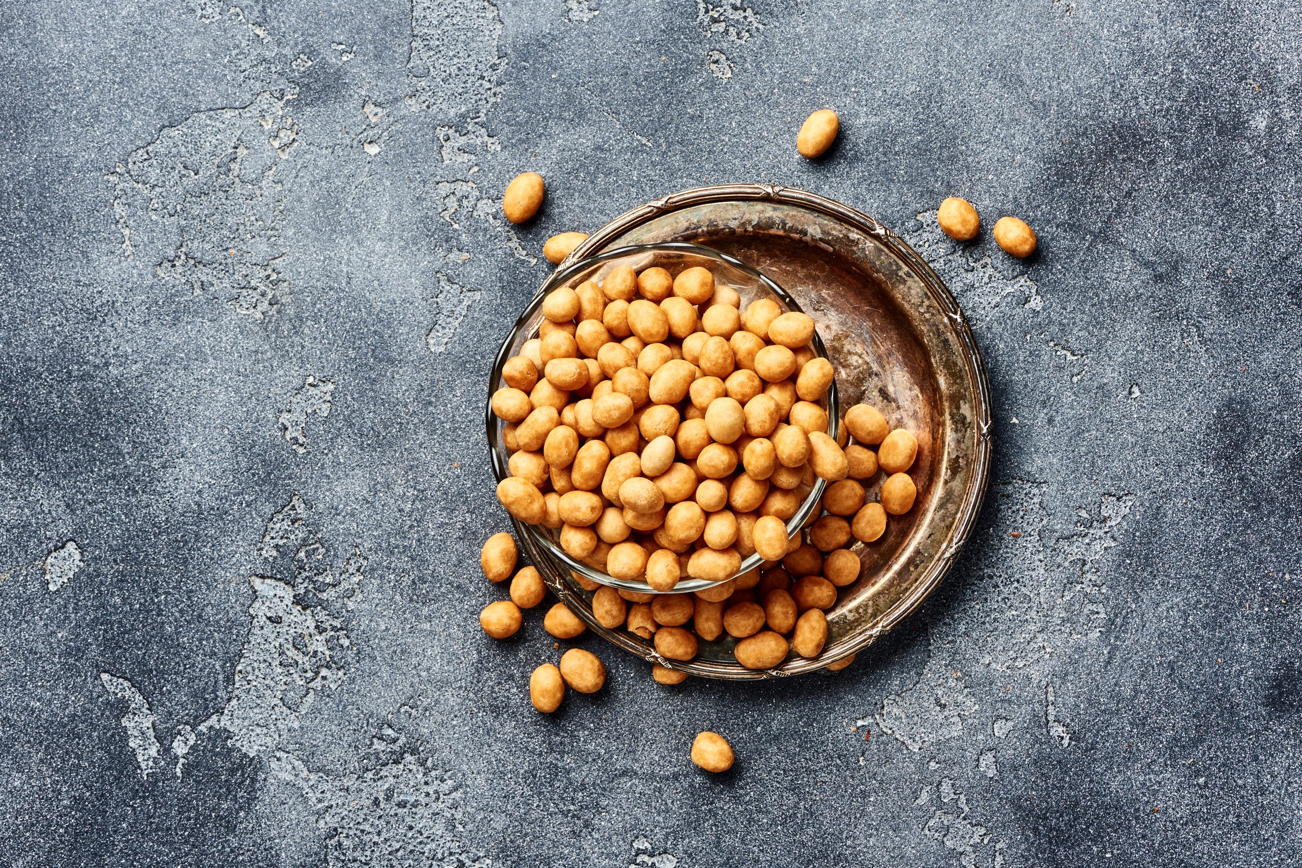 bowl full of battered nuts (japanese nuts or coated nuts) on top of plate on silver surface