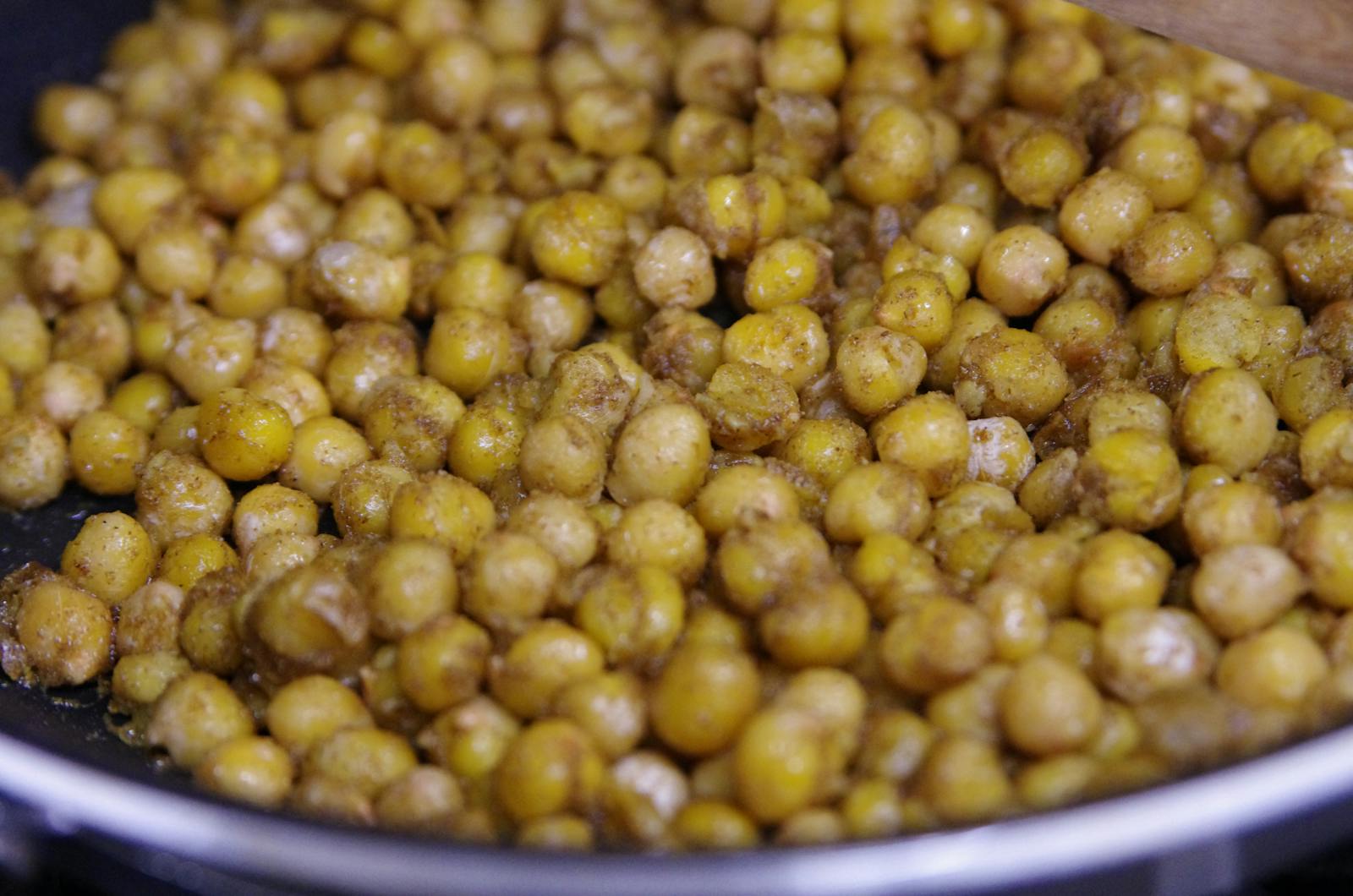 Appetizing roasted chickpeas seasoned with spices in a cooking pan.