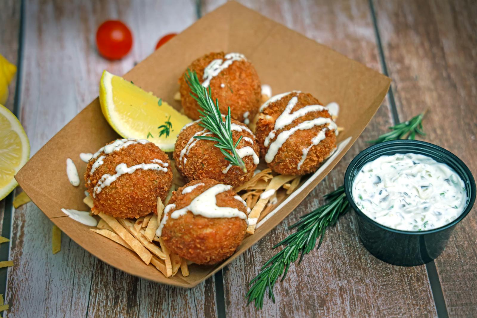 Delicious crispy crab cakes served with tartar sauce, garnished with rosemary and lemon.