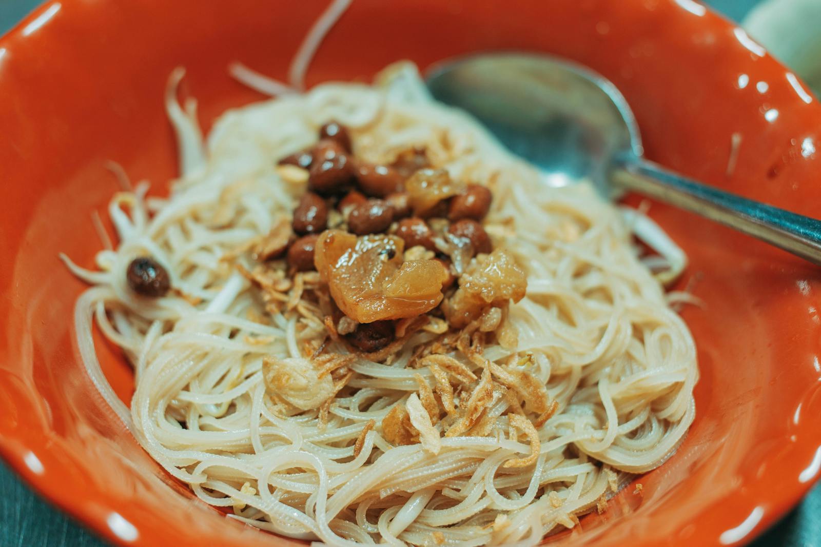 Close-up of a tasty Asian noodle dish with savory toppings served in a red bowl.