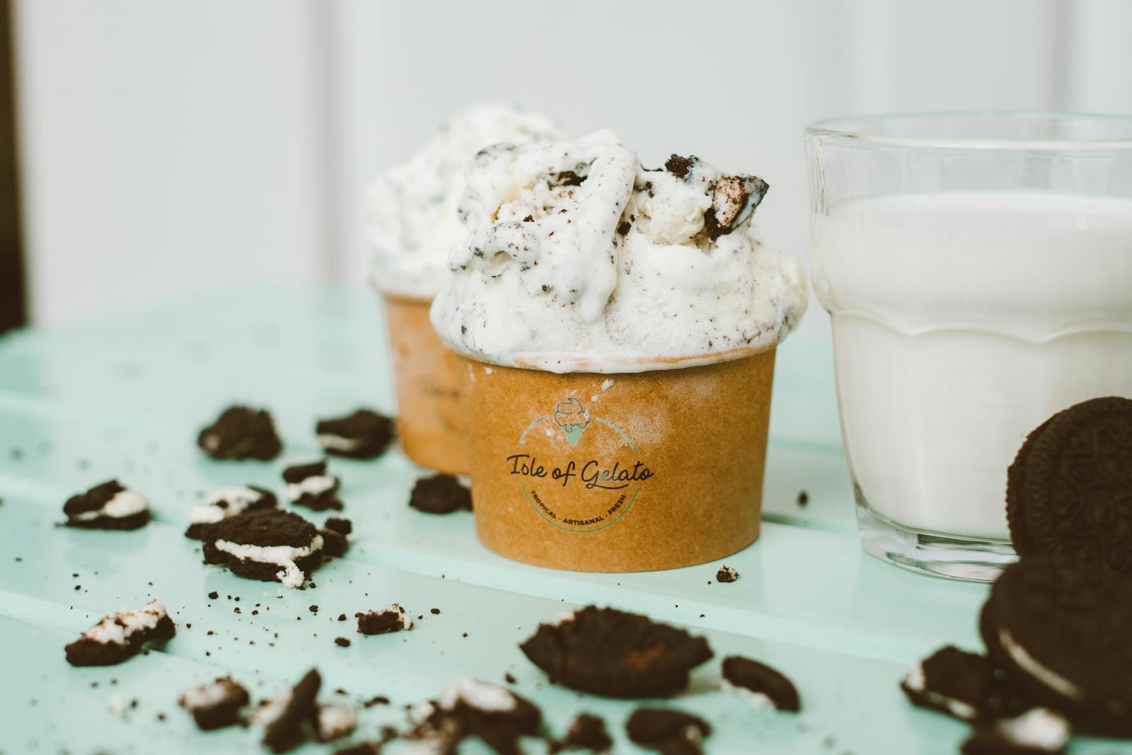 Delicious cookies and cream gelato in a paper cup paired with a glass of milk.