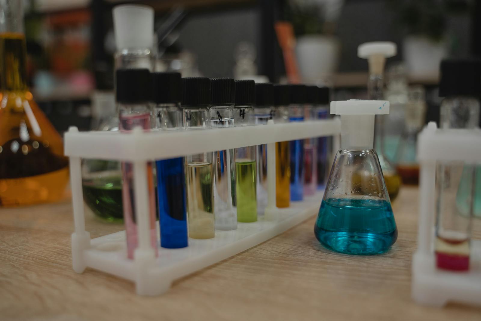 A collection of colorful test tubes and flasks in a chemistry laboratory setting.