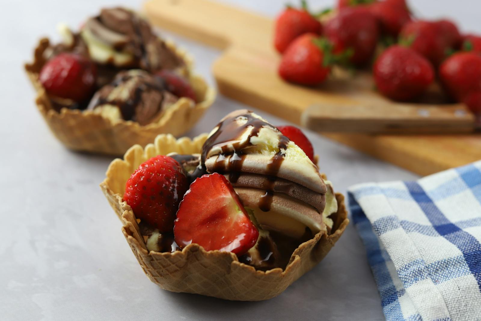 Close-up of chocolate and strawberry ice cream with syrup in a waffle cup.