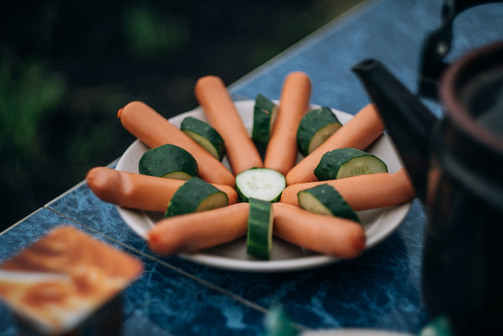close-up photo of sausage on plate with slice cucumber