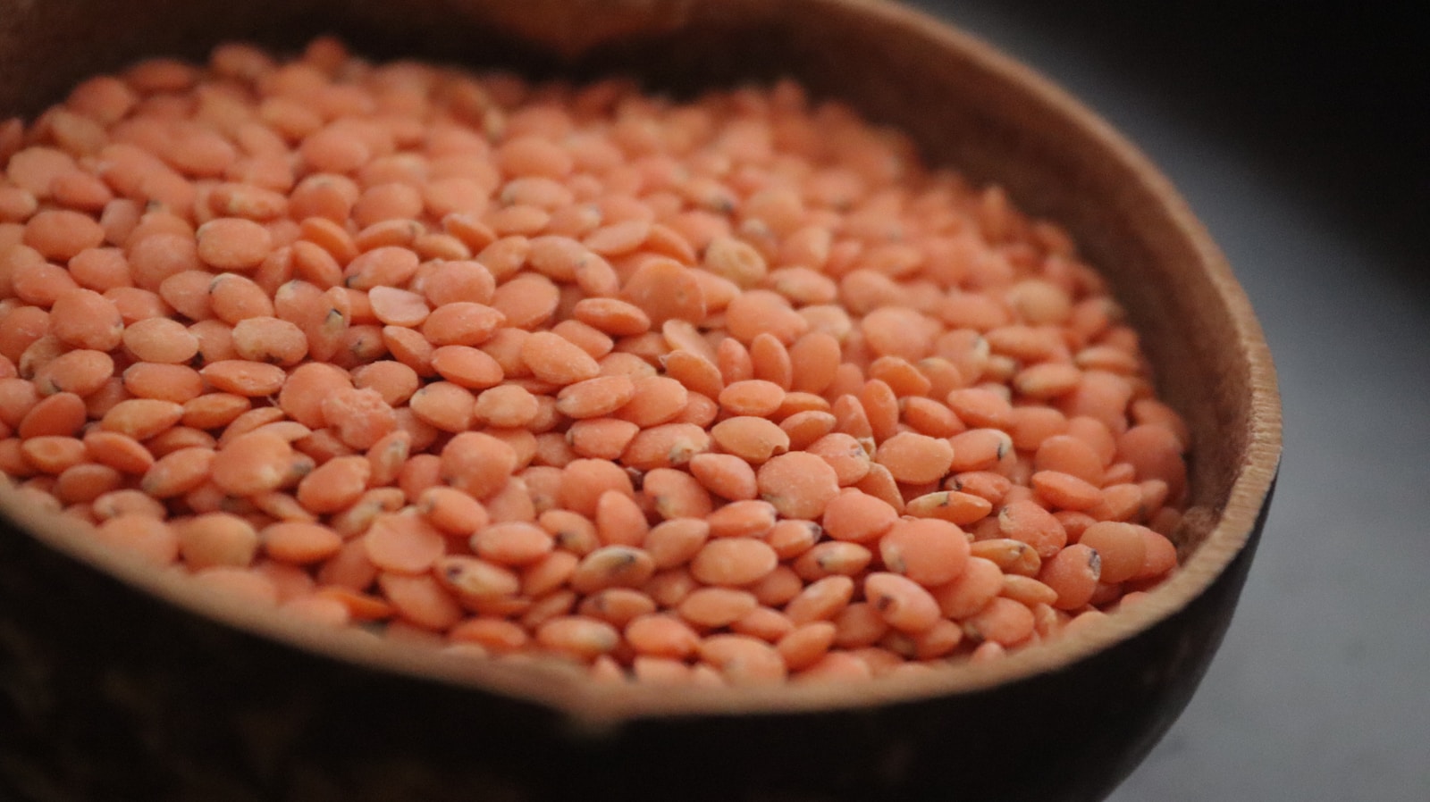 A wooden bowl filled with red beans on top of a table