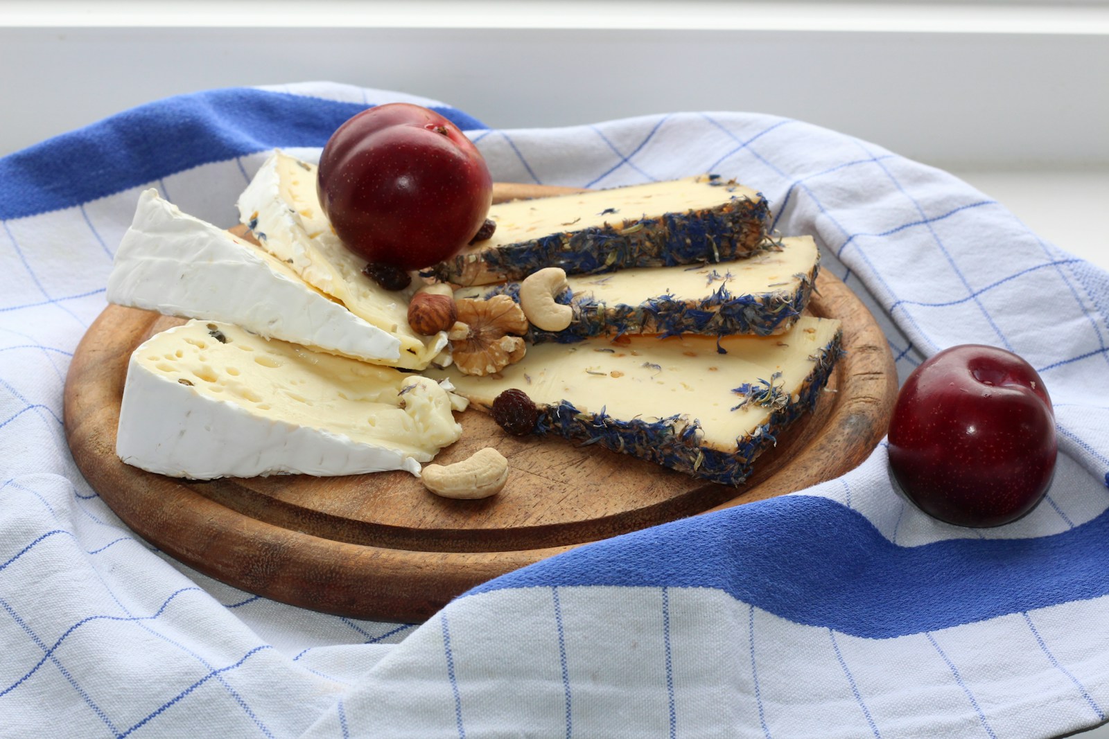 Cheese, fruit, and nuts are arranged on a board.